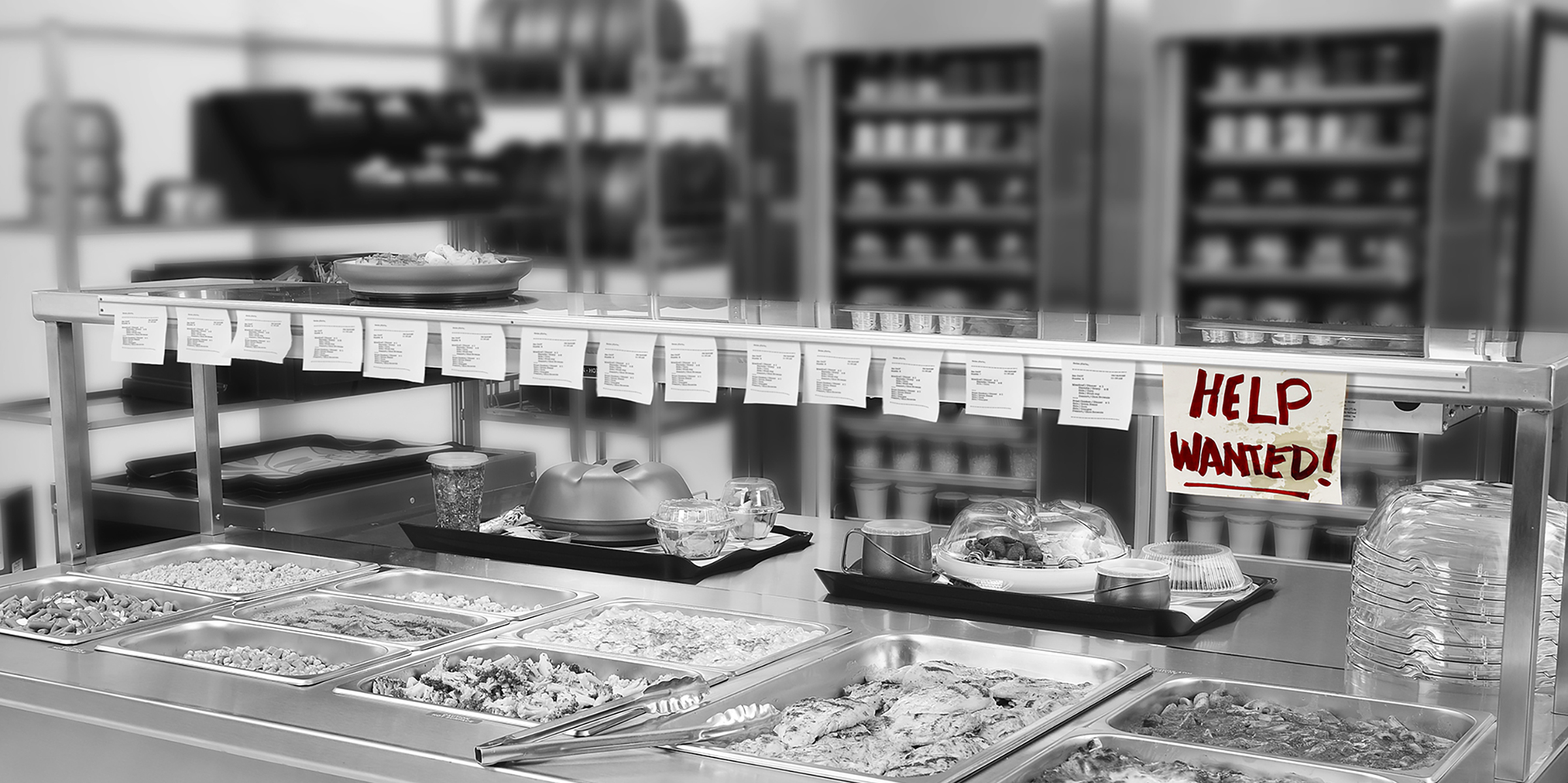 black and white image of kitchen with long list of order tickets and help wanted sign, Aladdin products in the background